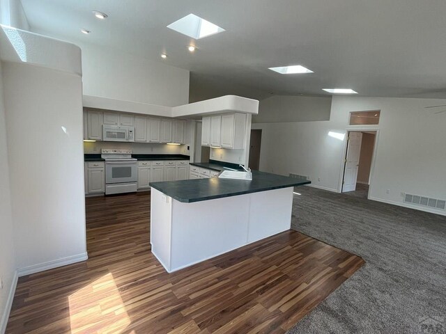 165 Kingsley Ave Unit M, Pueblo, CO 81005 - kitchen featuring white appliances, a skylight, dark countertops, a sink, and vaulted ceiling