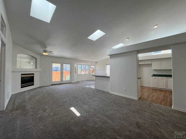 165 Kingsley Ave Unit M, Pueblo, CO 81005 - unfurnished living room with a skylight, carpet floors, baseboards, a glass covered fireplace, and ceiling fan