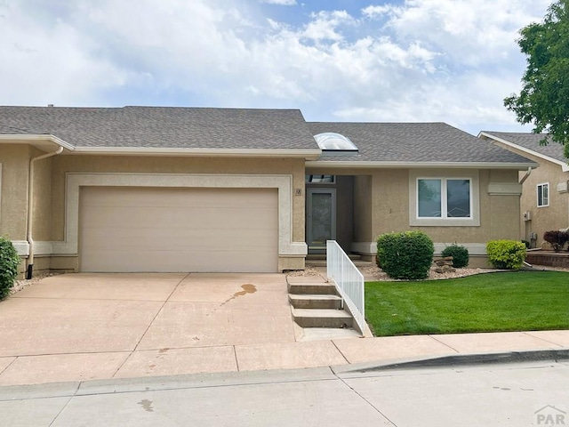 165 Kingsley Ave Unit M, Pueblo, CO 81005 - view of front facade with concrete driveway, stucco siding, an attached garage, a front yard, and roof with shingles
