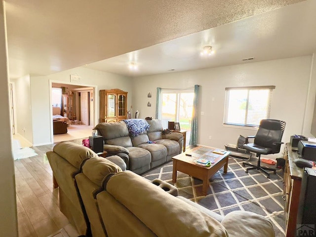 living area featuring baseboards, visible vents, and wood finished floors