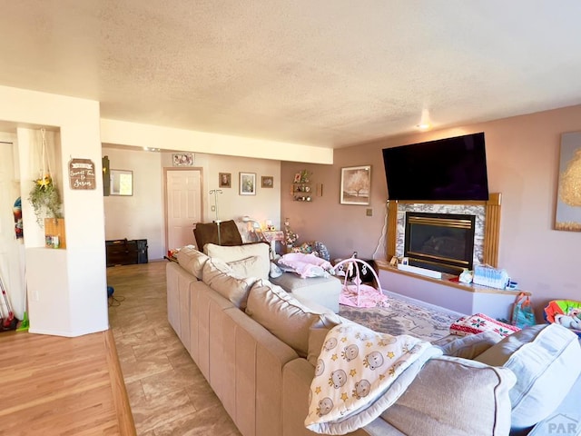 living area featuring light wood-style flooring, a premium fireplace, and a textured ceiling