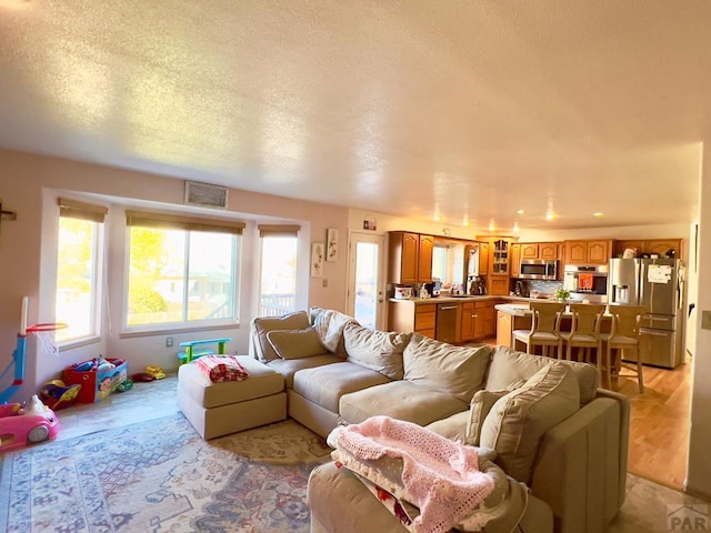 living area with light wood-type flooring and a textured ceiling