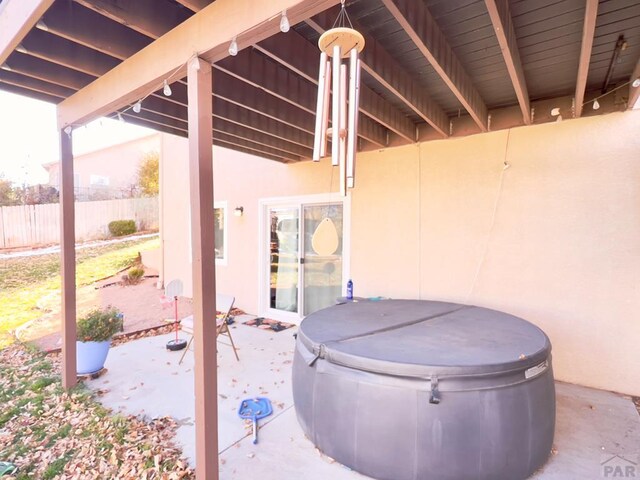 view of patio featuring fence and a hot tub