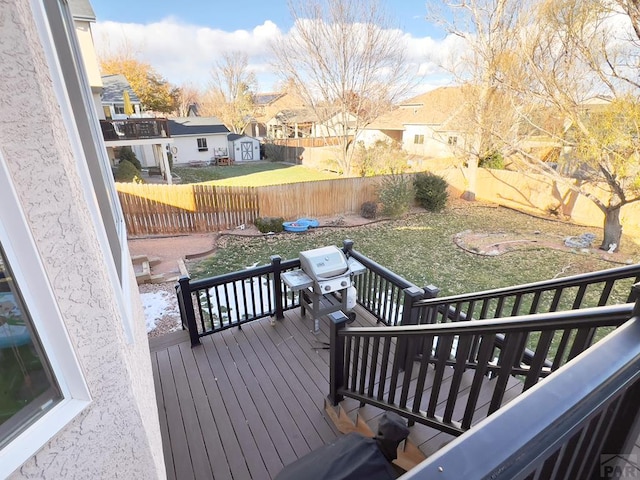 wooden terrace featuring a fenced backyard, a residential view, a shed, and an outdoor structure