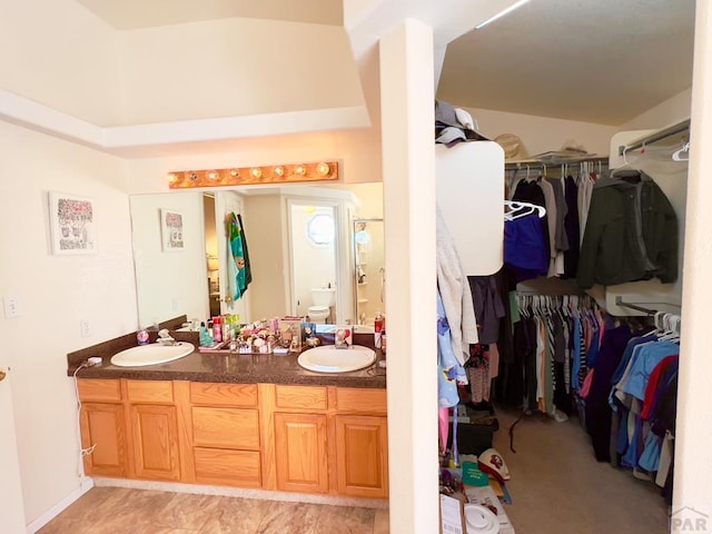 full bathroom featuring a sink, a spacious closet, toilet, and double vanity