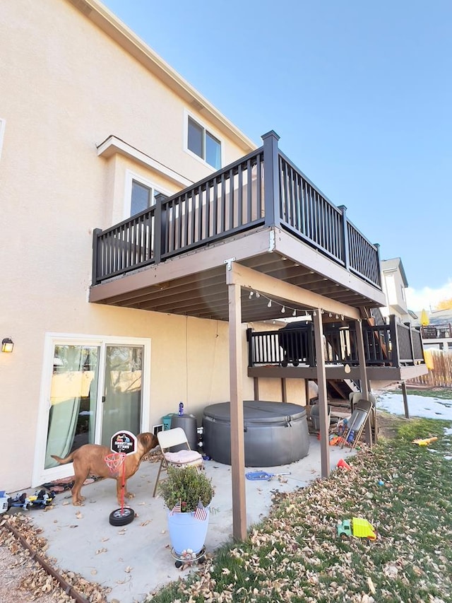 exterior space with a patio area, a hot tub, and stucco siding