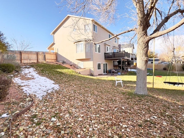 rear view of house with a yard, a fenced backyard, a wooden deck, and stucco siding