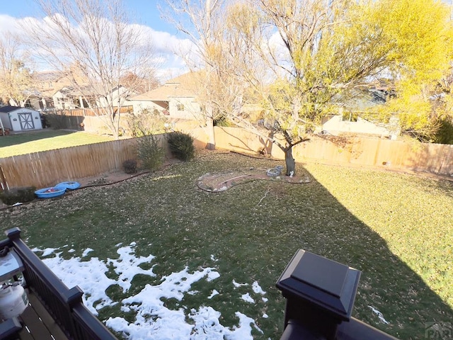 view of yard with a fenced backyard and a storage unit