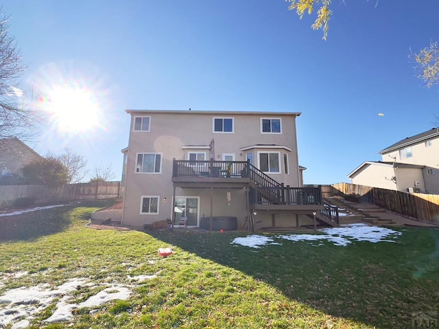 back of house featuring a fenced backyard, stairs, a deck, a yard, and stucco siding