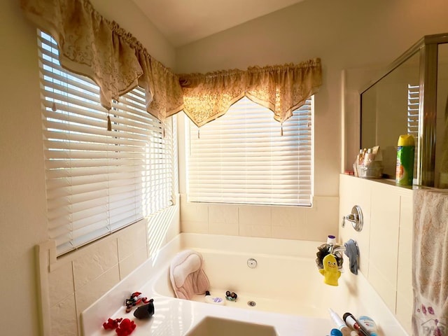 bathroom featuring vaulted ceiling and a bath