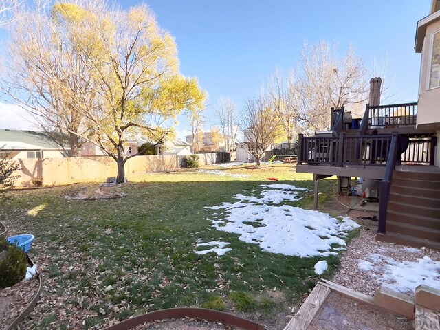 yard layered in snow featuring a fenced backyard, stairway, and a deck