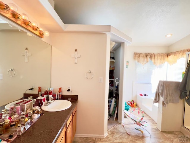 full bath featuring a bath, a shower with door, vanity, and baseboards