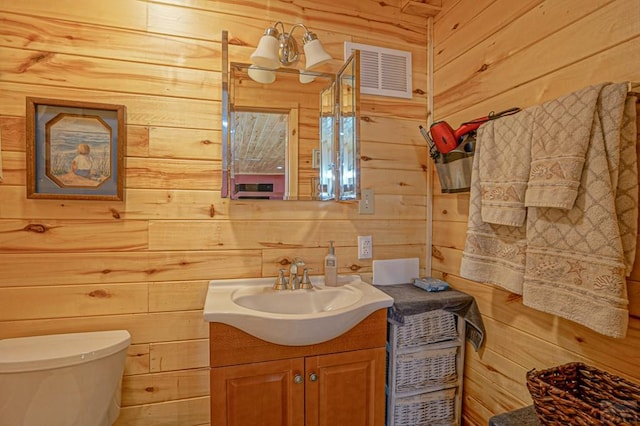 bathroom featuring toilet, a notable chandelier, wood walls, visible vents, and vanity