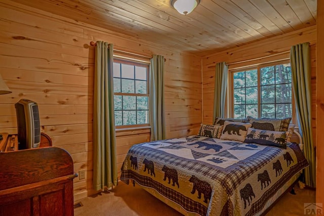 bedroom featuring carpet, multiple windows, wood walls, and wooden ceiling