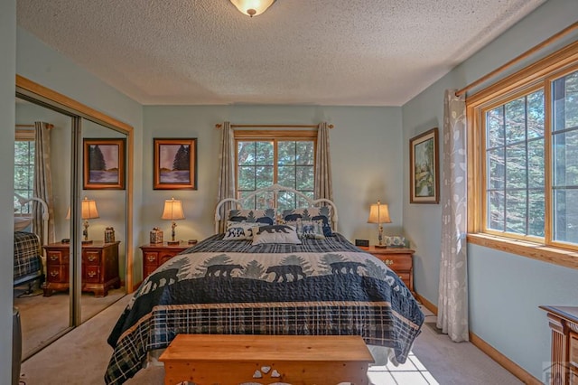 bedroom featuring light carpet, a closet, baseboards, and a textured ceiling