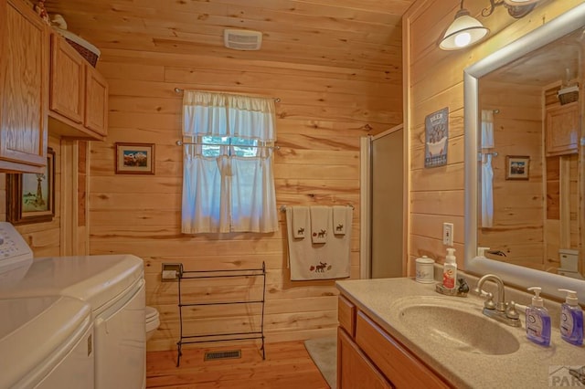 bathroom with wooden walls, wood ceiling, visible vents, vanity, and washer and clothes dryer