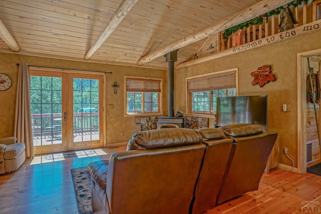 living area with vaulted ceiling with beams, wood ceiling, a wood stove, and light wood-style floors