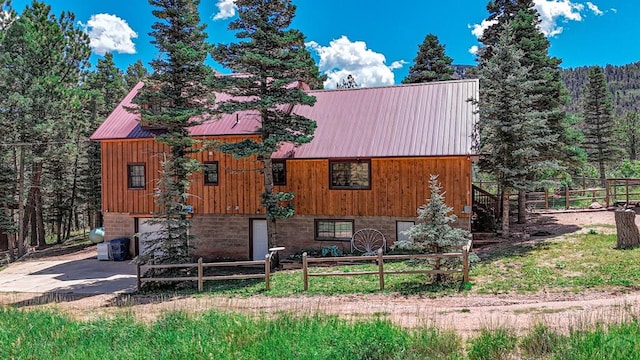 chalet / cabin with metal roof, driveway, and an attached garage