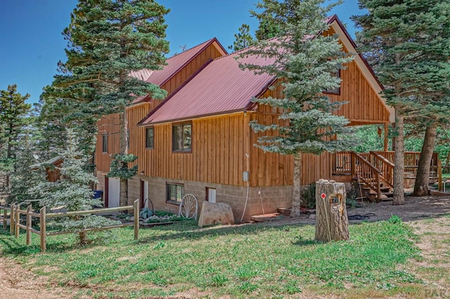 view of side of home with metal roof, a lawn, and fence