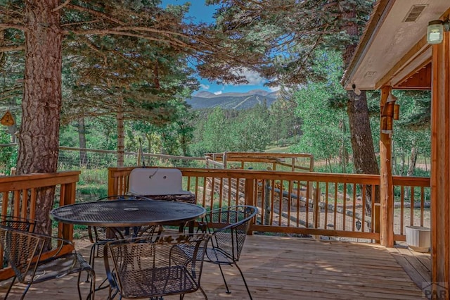 deck with outdoor dining area and a mountain view