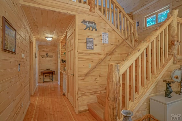 interior space featuring wooden ceiling, wood walls, stairway, and light wood finished floors