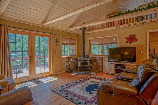 living room featuring lofted ceiling with beams, wooden ceiling, wood finished floors, a wood stove, and french doors