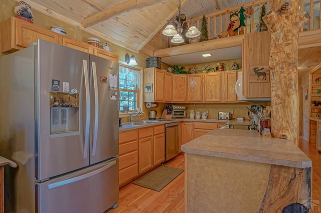 kitchen featuring appliances with stainless steel finishes, light countertops, a sink, and light brown cabinetry