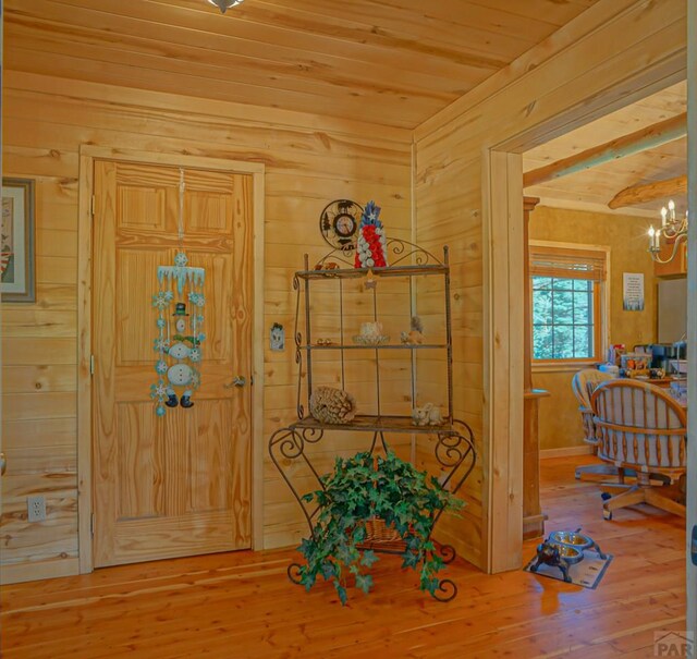 entryway featuring wood walls, wood finished floors, wood ceiling, and a notable chandelier