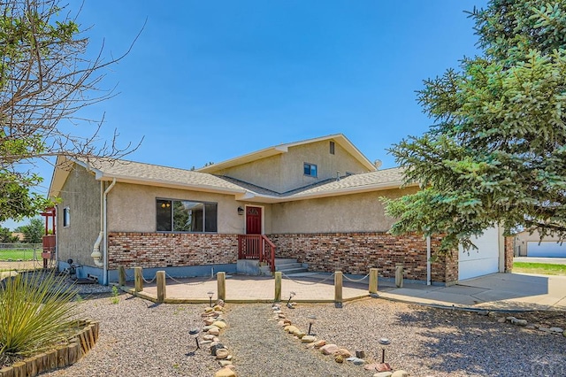 950 S Los Charros Dr, Pueblo West, CO 81007 - view of front of house with stucco siding, a garage, brick siding, concrete driveway, and roof with shingles