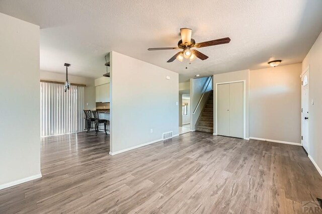 950 S Los Charros Dr, Pueblo West, CO 81007 - unfurnished living room featuring ceiling fan, wood finished floors, and stairway
