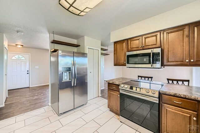 950 S Los Charros Dr, Pueblo West, CO 81007 - kitchen featuring appliances with stainless steel finishes, dark countertops, and brown cabinets