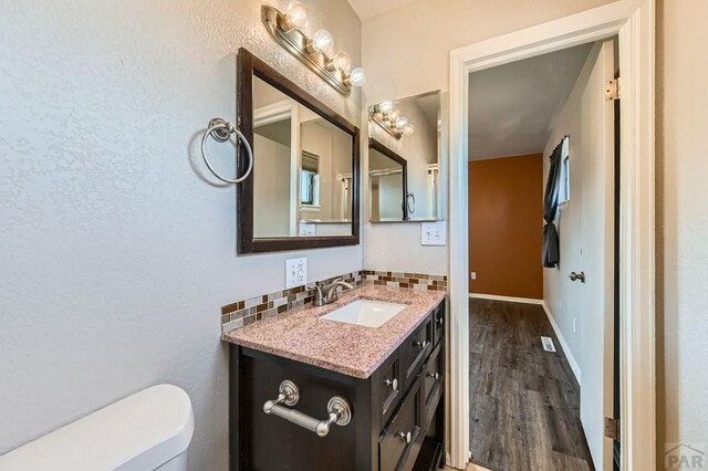 950 S Los Charros Dr, Pueblo West, CO 81007 - half bathroom featuring vanity, tasteful backsplash, and wood finished floors