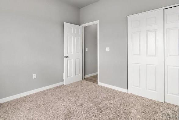 unfurnished bedroom featuring a closet, carpet flooring, and baseboards