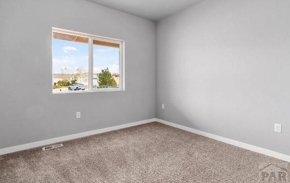 carpeted spare room featuring visible vents and baseboards