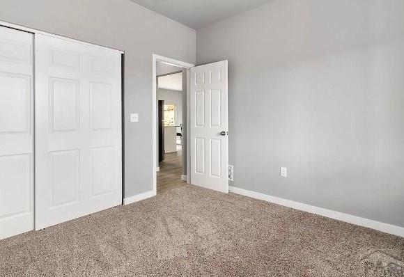 unfurnished bedroom with a closet, baseboards, and carpet floors