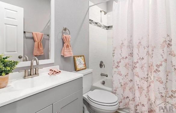 full bathroom with toilet, vanity, and shower / bathtub combination with curtain