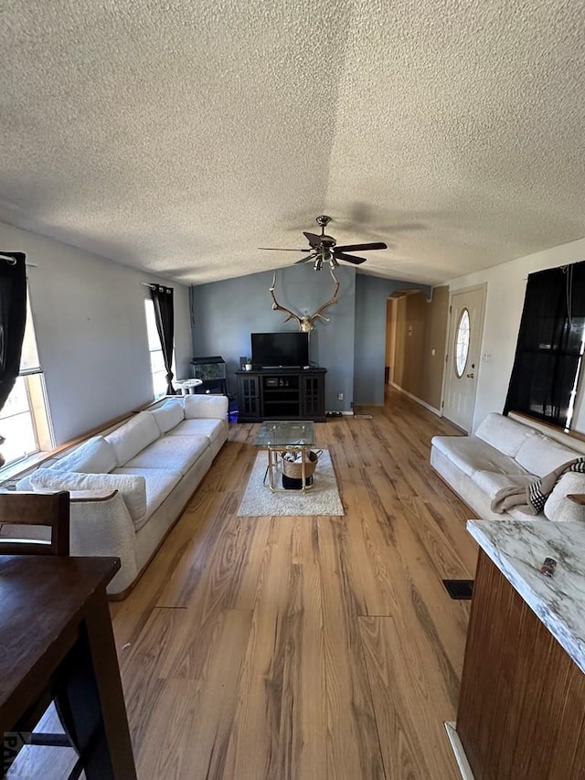 unfurnished living room with ceiling fan, a textured ceiling, and light wood finished floors