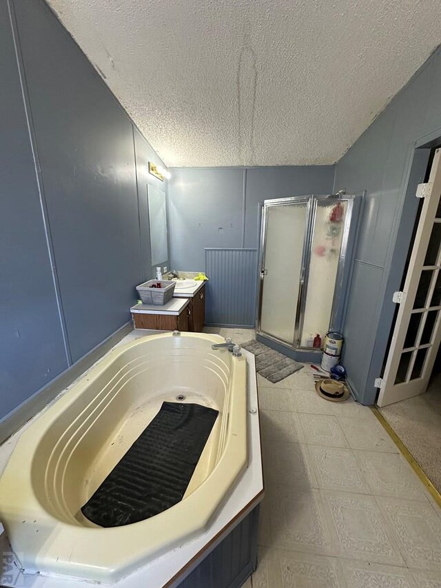 bathroom with a shower stall, vanity, a textured ceiling, a tub with jets, and tile patterned floors