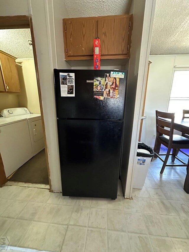 kitchen featuring brown cabinets, independent washer and dryer, freestanding refrigerator, light countertops, and a textured ceiling