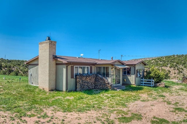 back of property featuring a chimney, fence, and a yard