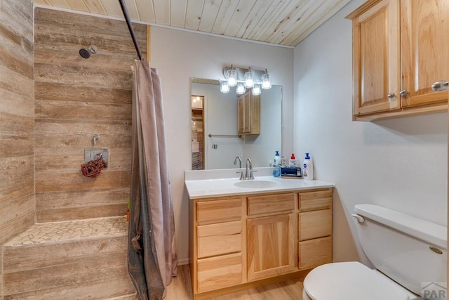 bathroom featuring toilet, tiled shower, wooden ceiling, and vanity