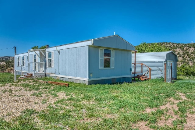 view of property exterior with a storage shed, a lawn, and an outbuilding