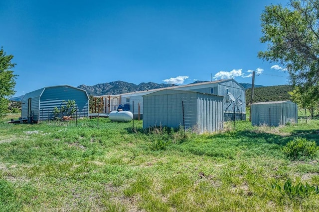 view of yard featuring an outbuilding, a mountain view, and a storage shed