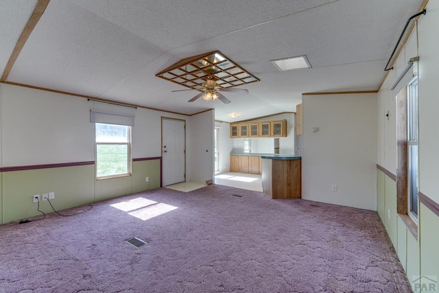 unfurnished living room featuring light carpet, visible vents, lofted ceiling, ceiling fan, and a textured ceiling