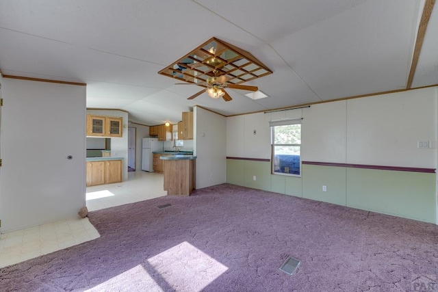 interior space featuring a ceiling fan, lofted ceiling, visible vents, and light carpet