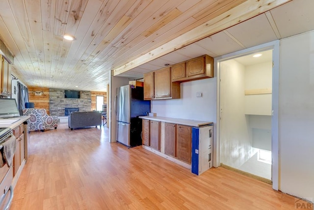 kitchen featuring brown cabinetry, freestanding refrigerator, light countertops, and light wood finished floors