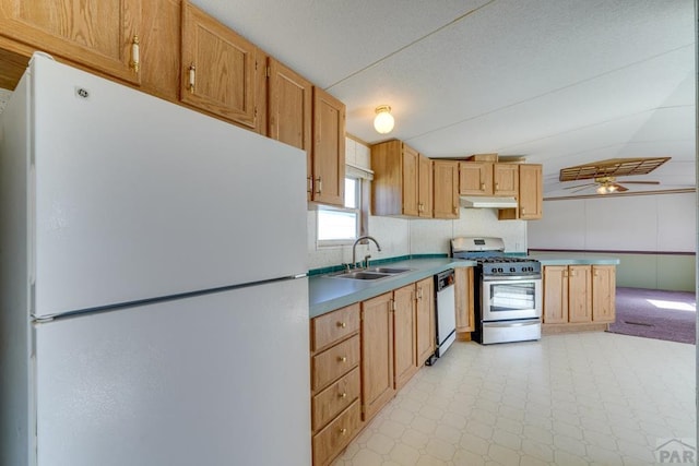 kitchen featuring dishwashing machine, under cabinet range hood, a sink, freestanding refrigerator, and gas range