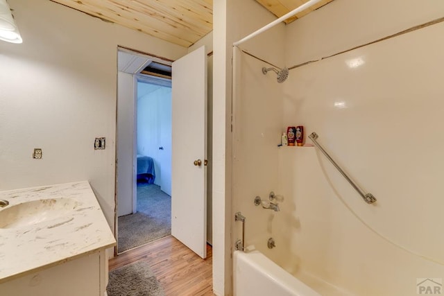 full bath with ensuite bathroom, shower / bath combination, wood finished floors, and vanity