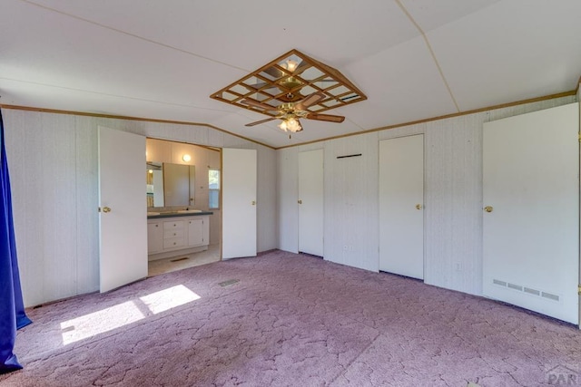 unfurnished bedroom with lofted ceiling, connected bathroom, crown molding, and light colored carpet