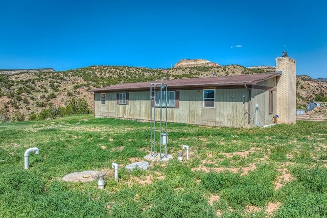 exterior space featuring a yard, a chimney, and a mountain view